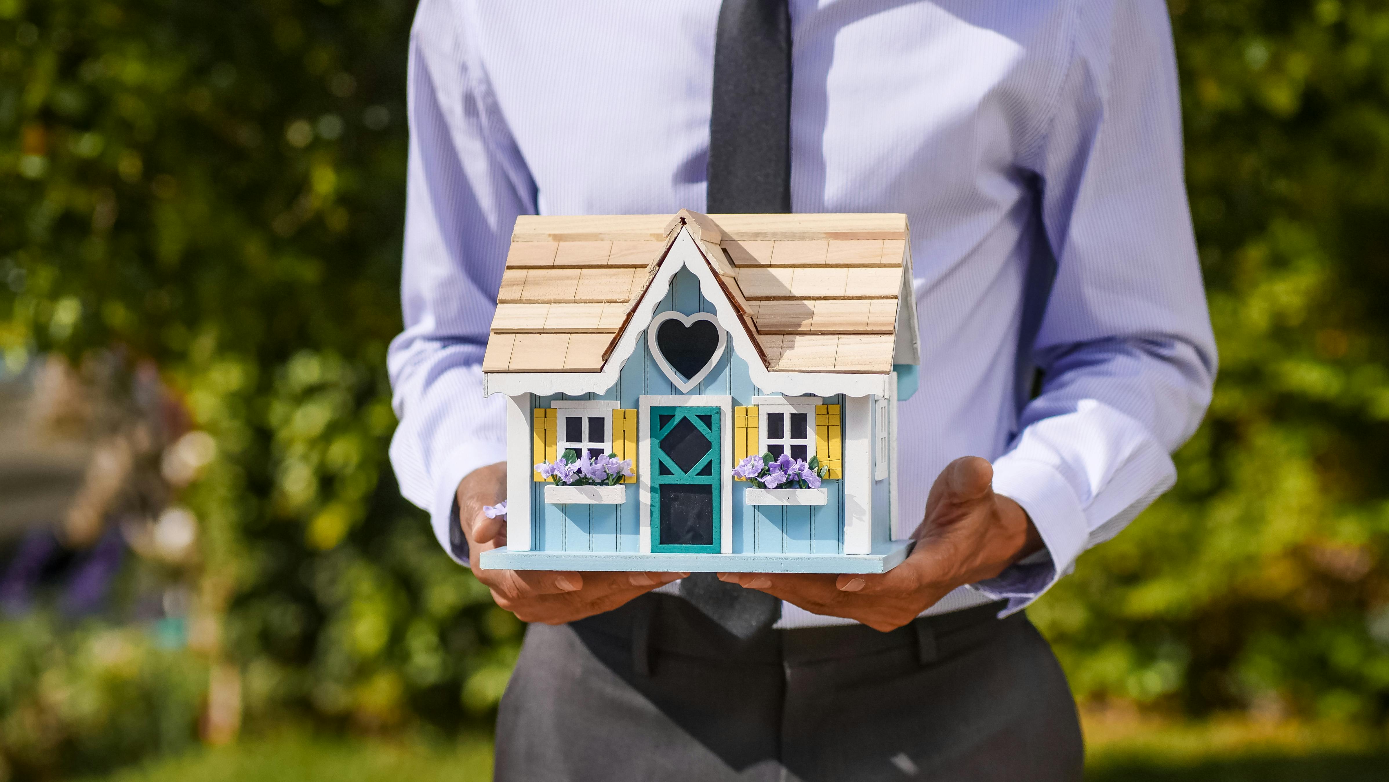 person holding a model house